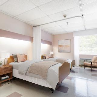 A spacious and well-lit hospital room featuring two separate beds and calming decor.