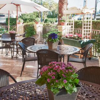 A charming outdoor cafe patio with tables, chairs, and blooming flowers.