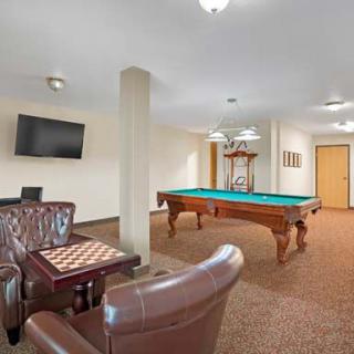 A spacious game room featuring a billiards table, chess board, and comfortable seating.