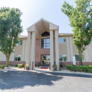 A modern office building with a prominent entrance surrounded by trees.