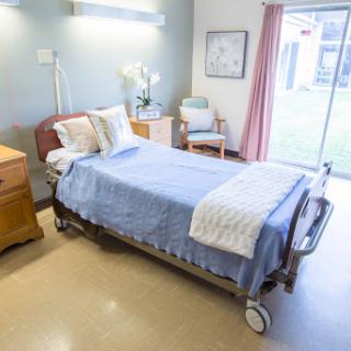 A calm and clean hospital patient room featuring a bed, bedside table, and ample natural light.