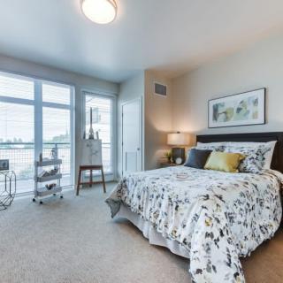 A modern and cozy bedroom with a large window allowing natural light, featuring stylish decor and comfortable bedding.