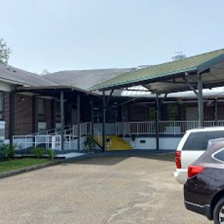 View of a facility entrance with a covered walkway and parked cars.