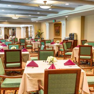 An elegant dining hall with neatly arranged tables and chairs, adorned with decorative napkins and flowers.