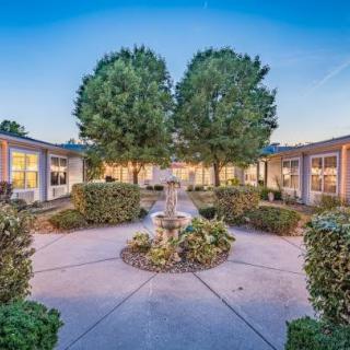 A serene courtyard with a central fountain, surrounded by lush greenery and buildings.