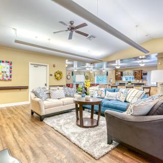 A spacious and well-decorated living room with comfortable sofas, wooden flooring, and ample lighting.
