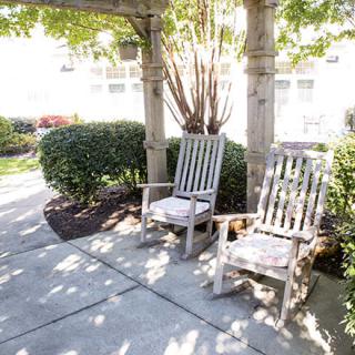 Two rocking chairs on a sunny patio surrounded by lush greenery.