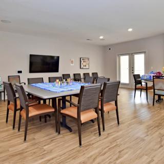 A spacious dining or meeting room with a large table, several chairs, and a wall-mounted television.