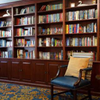 A cozy library corner featuring a well-stocked bookshelf and a comfortable chair.