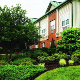 A well-landscaped residential building with a brick facade and lush greenery.
