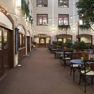 A cozy indoor courtyard with restaurant seating and string lights.