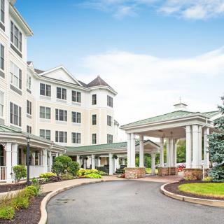 A large residential building with a covered entrance and landscaped driveway.