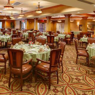 An elegant dining room with neatly arranged tables and chairs, featuring warm lighting and decor.