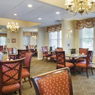 An elegantly decorated dining area with chandeliers, carpeted flooring, and neatly arranged tables and chairs.