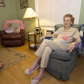 An elderly woman sitting comfortably in a cozy living room.