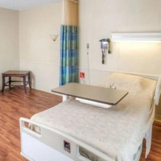 A hospital room featuring a standard patient bed and basic amenities.