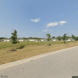 A suburban landscape with a road, trees, and a clear sky.