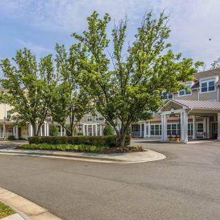 A building with a driveway surrounded by well-maintained trees and landscaping.