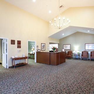 A spacious office reception area with a central desk and a waiting area in the background.