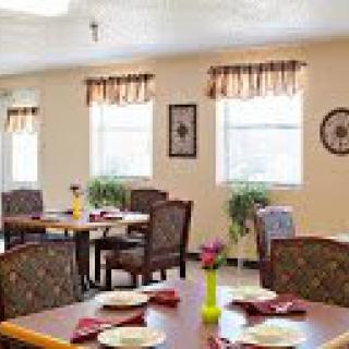 A cozy dining area with neatly arranged tables and chairs, decorated with plants and wall art.