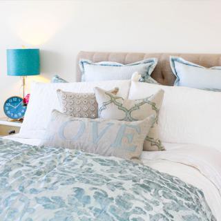 A cozy and stylish bedroom with elegant bedding and decorative pillows.