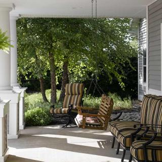 A cozy porch with comfortable chairs overlooking a lush garden.