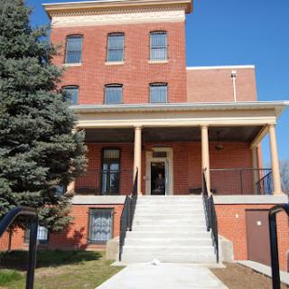 A historical brick building with a welcoming front entrance and steps leading up to it.