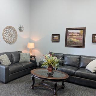 A cozy living room setup featuring comfortable sofas, a coffee table with floral arrangement, and decorative wall art.