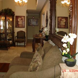 A cozy living room with a sofa, decorative mirror, and plants.