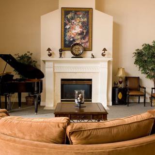A cozy living room with a fireplace, grand piano, and stylish decor.