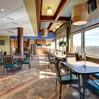 A spacious and modern dining area featuring large windows, comfortable seating, and a warm atmosphere.