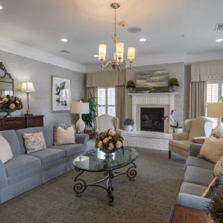 A cozy and elegantly designed living room featuring a chandelier, fireplace, and comfortable seating.