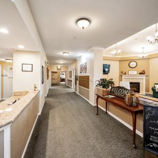 A well-lit hallway with carpeted floors and a reception area featuring decorative elements and furniture.