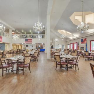 An elegant dining hall with chandeliers, featuring neatly arranged tables and chairs in a spacious setting.
