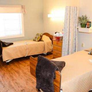 A cozy nursing home room with two twin beds and comfortable furnishings.