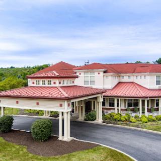 A beautiful residential building with a red tile roof, set against a scenic landscape.