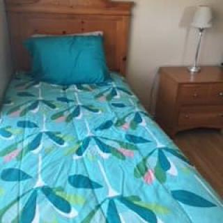 A neatly made bed with colorful bedding and a wooden nightstand with a lamp.