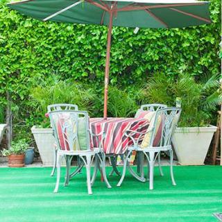 A colorful outdoor patio set with an umbrella amid lush greenery.