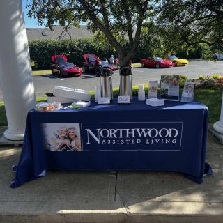 An outdoor event table for Northwood Assisted Living featuring brochures and a coffee setup.