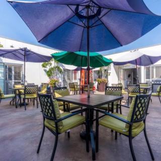 A sunny outdoor patio with tables, chairs, and colorful umbrellas.