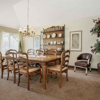 A traditional dining room with a wooden table and chairs, a chandelier, and a cabinet displaying plates.