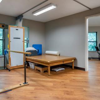 A spacious rehabilitation room featuring wooden flooring and exercise equipment.