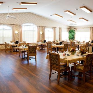 Spacious dining room with wooden floors and neatly arranged tables and chairs.