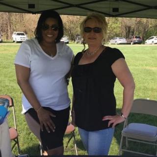 Two people standing together under a tent on a sunny day.