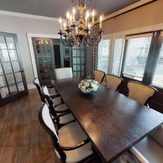 A well-furnished dining room with a wooden table, elegant chairs, and a chandelier.