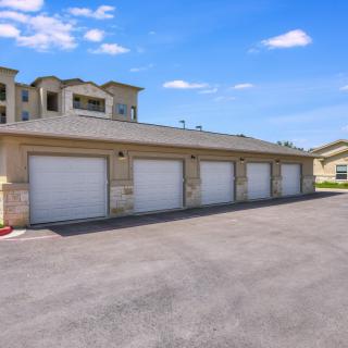 A row of residential garages in a modern apartment complex under a clear blue sky.