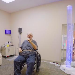 An elderly person sitting in a wheelchair in a rehabilitation setting, engaged in therapy.
