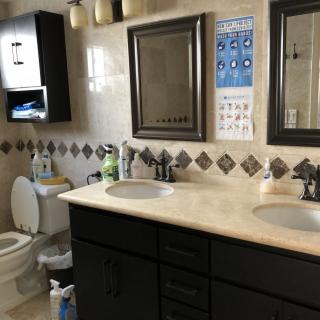 A well-organized bathroom featuring dual sinks, a toilet, and decorative tiles.