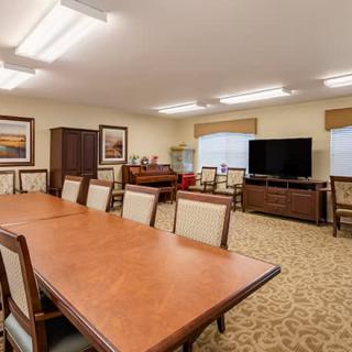 A spacious conference room equipped with a large meeting table, several chairs, and a television.