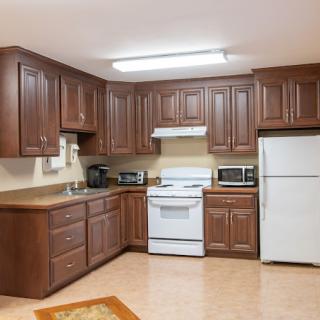 A kitchen with wooden cabinets, equipped with a white stove, refrigerator, and microwave.